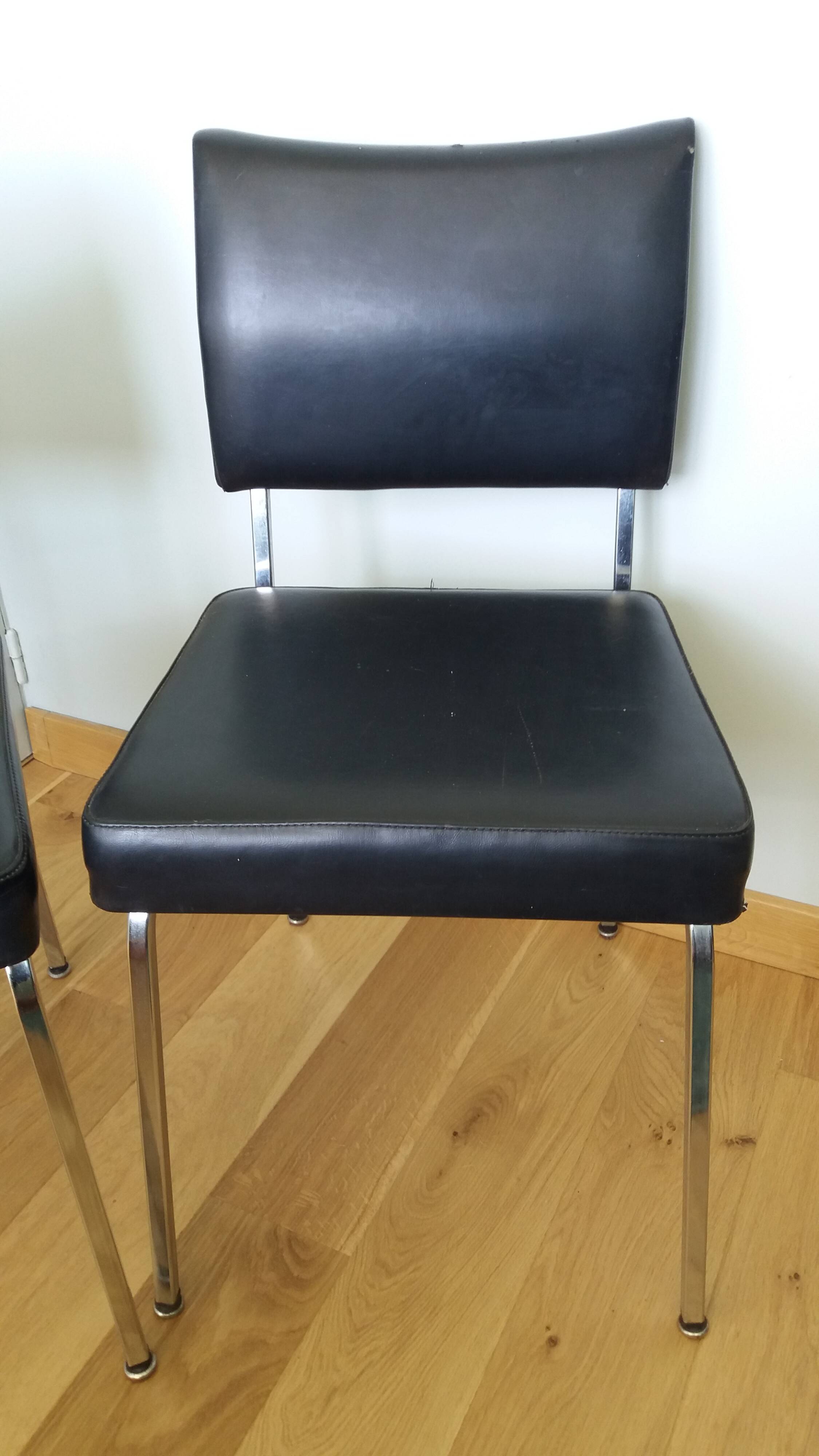 Chrome metal chairs and black faux leather upholstery in retro modernist style.