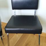 Chrome metal chairs and black faux leather upholstery in retro modernist style.