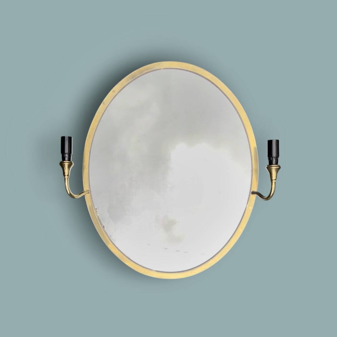Oval wall mirror in gilded brass with double sconces – 1950s/60s