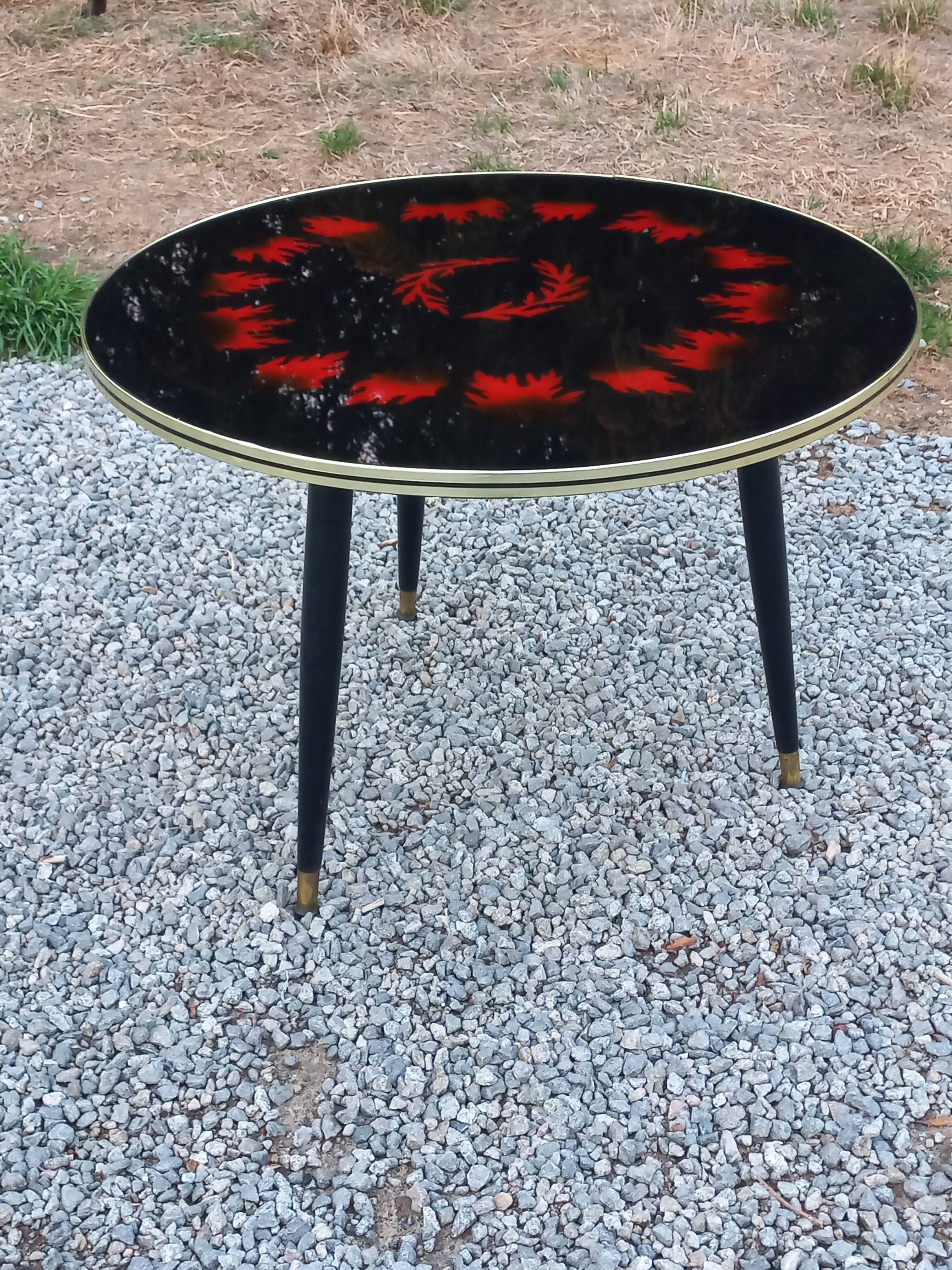 Vintage coffee table with glass top and tripod legs in blackened wood from the 1960s.