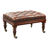 Ottoman en cuir marron de style Chesterfield avec des pieds ornés.