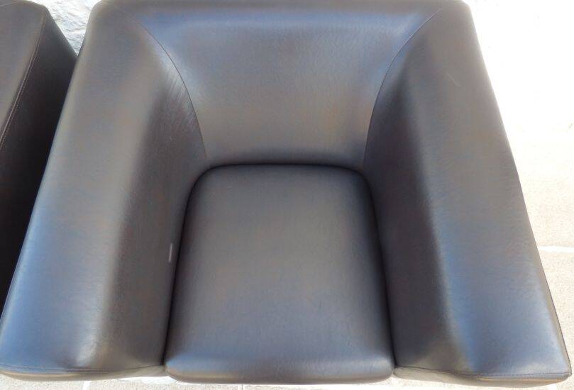 2 club armchairs with a chocolate faux leather seat and backrest and wooden legs.