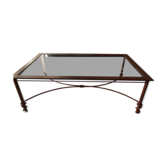 Table basse  en métal couleur rouille avec un plateau en verre.
