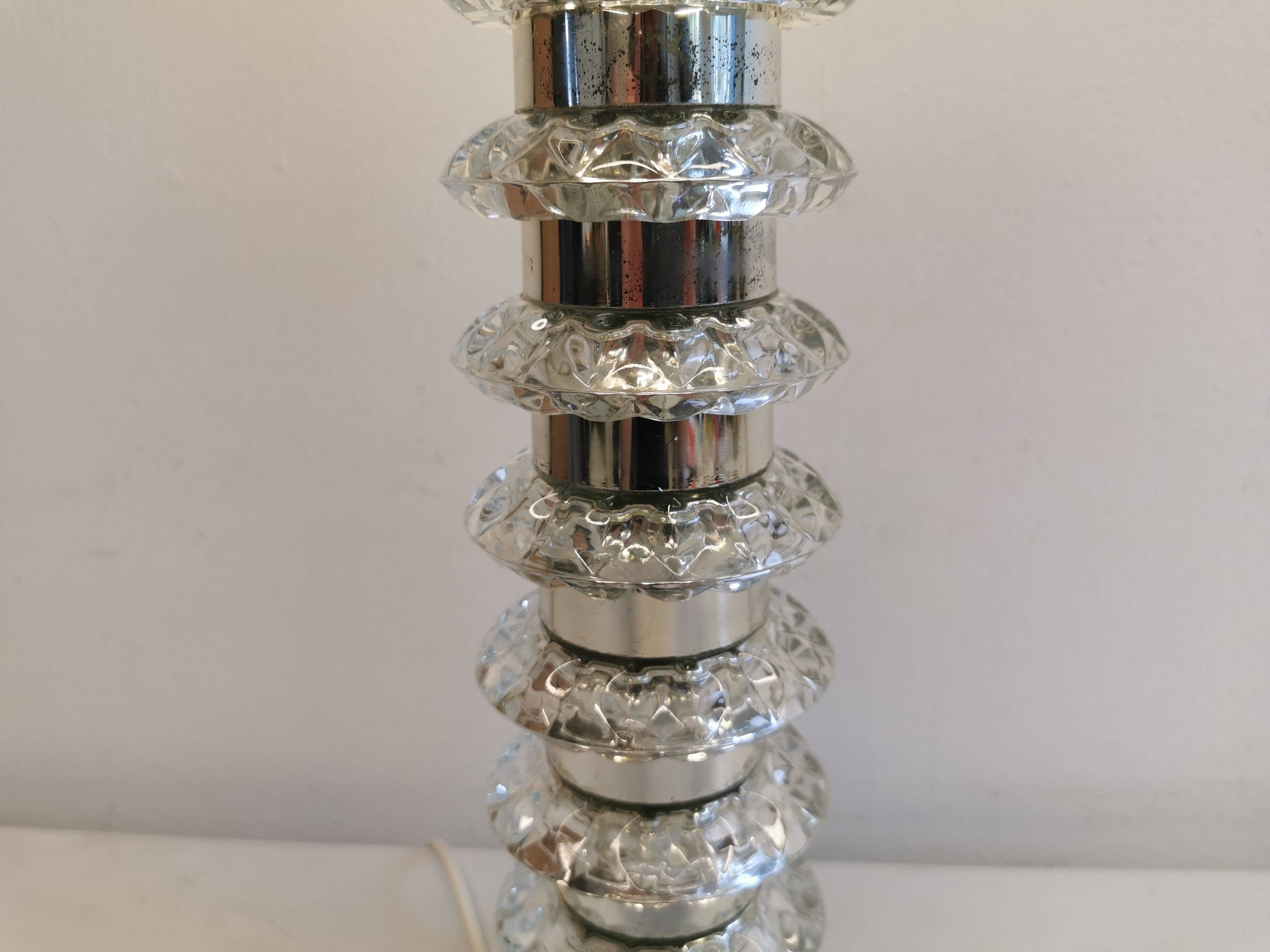 Table lamp made of transparent crystal glass and silver colored spacers.