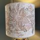 Table lamp with a solid wood printing roll and floral lampshade.