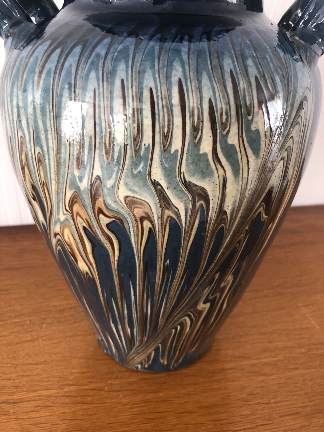 Vase in glazed ceramic decoration drips on blue background