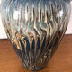 Vase in glazed ceramic decoration drips on blue background