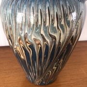 Vase in glazed ceramic decoration drips on blue background