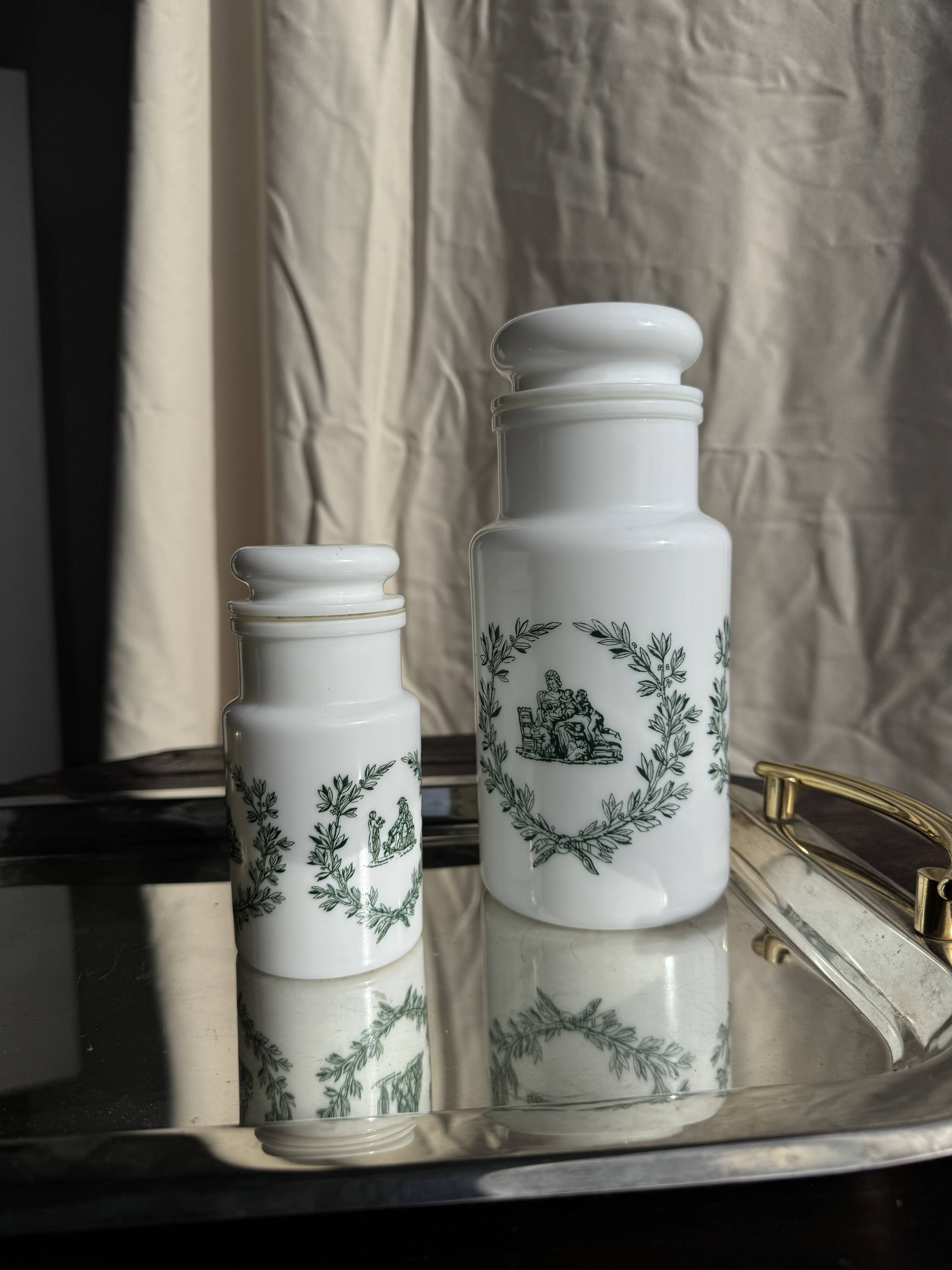 A pair of white glass bottles with Italian green patterns.