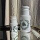 A pair of white glass bottles with Italian green patterns.