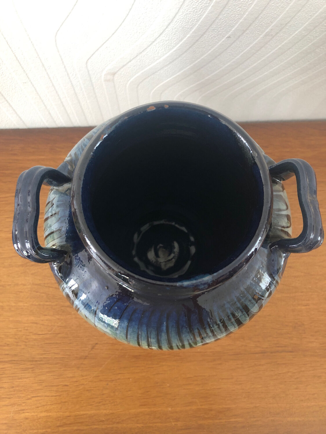 Vase in glazed ceramic decoration drips on blue background