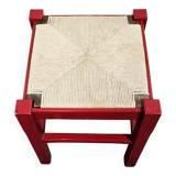 Red wooden stool with woven rush seat.