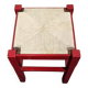 Tabouret en bois rouge avec assise en paille tressée.