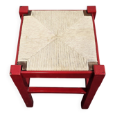Tabouret en bois rouge avec assise en paille tressée.