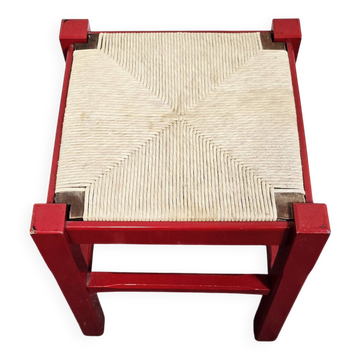Tabouret en bois rouge avec assise en paille tressée.