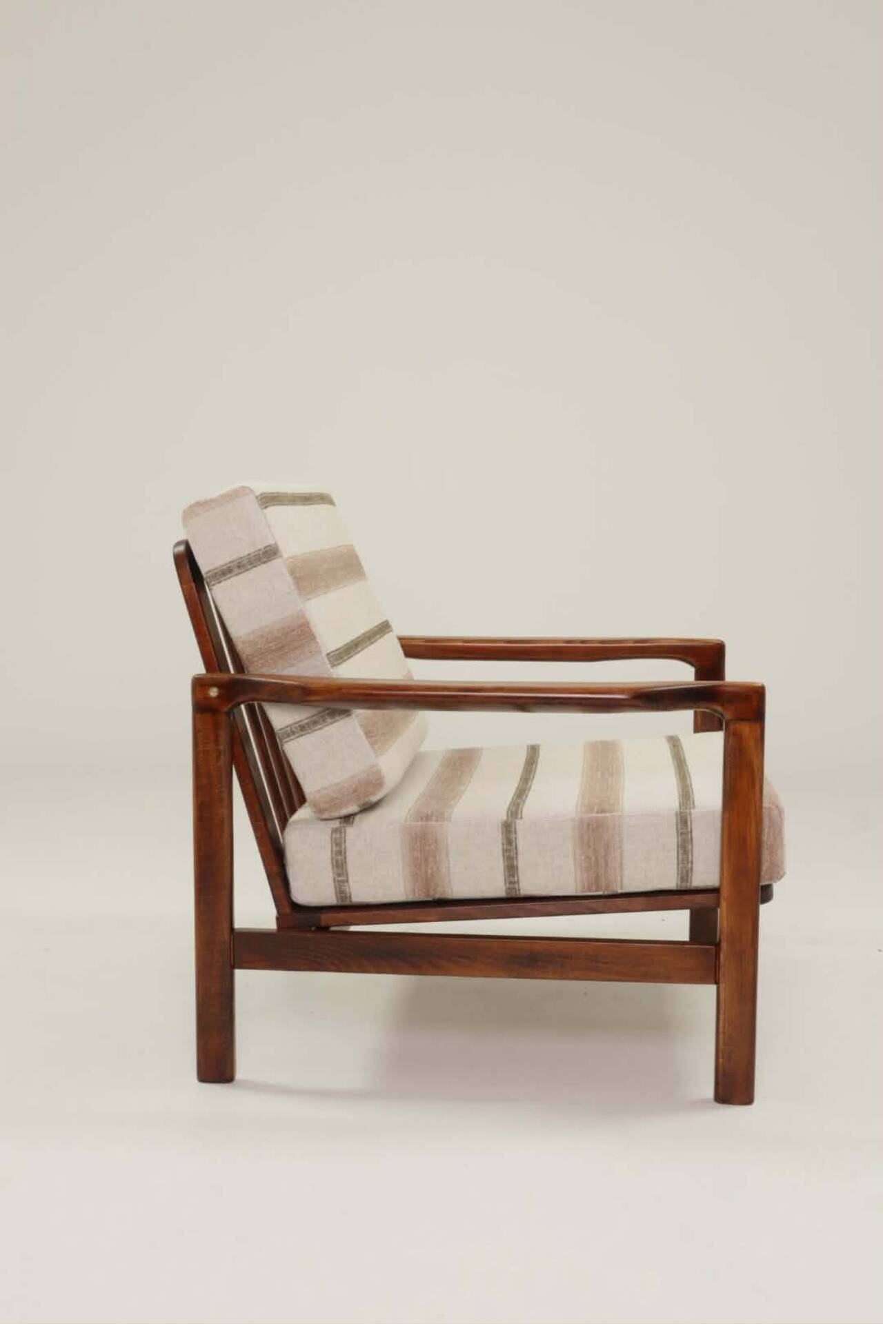 Fauteuil vintage avec des coussins en tissu naturel rayé.