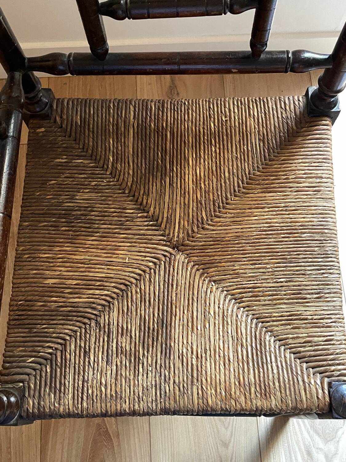 Corner chair made of turned wood with a straw seat.