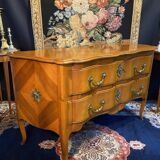 Large bow-fronted chest of drawers in blonde cherry with bronze ornamentation.