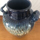 Vase in glazed ceramic decoration drips on blue background