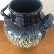 Vase in glazed ceramic decoration drips on blue background