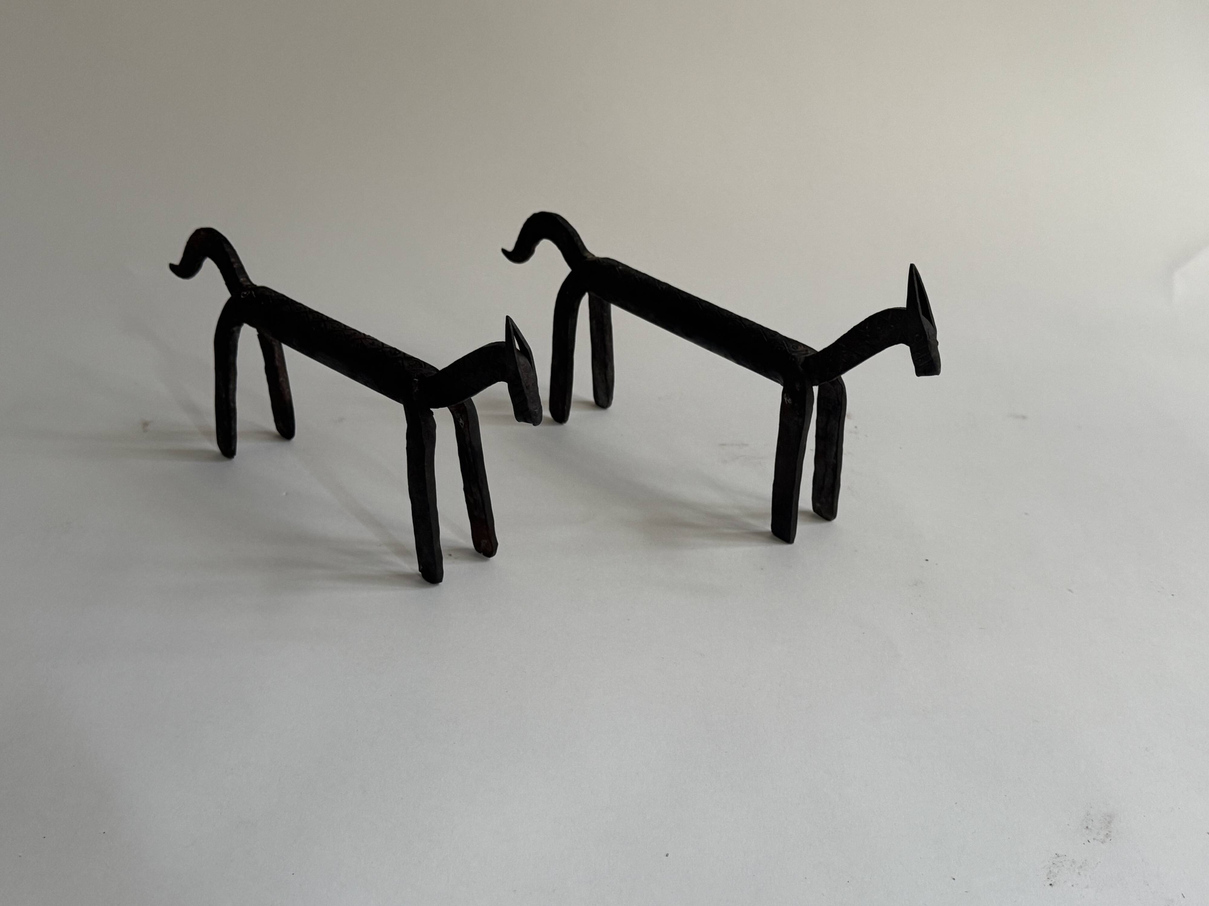 Pair of animal-shaped wrought iron and hammered fire dogs in primitive brutalist style.