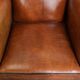 Large sheepskin wingback chair with black piping and decorative nails