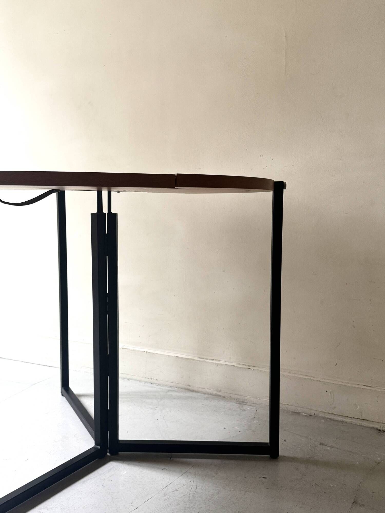 Modernist round folding dining table in wood and metal.