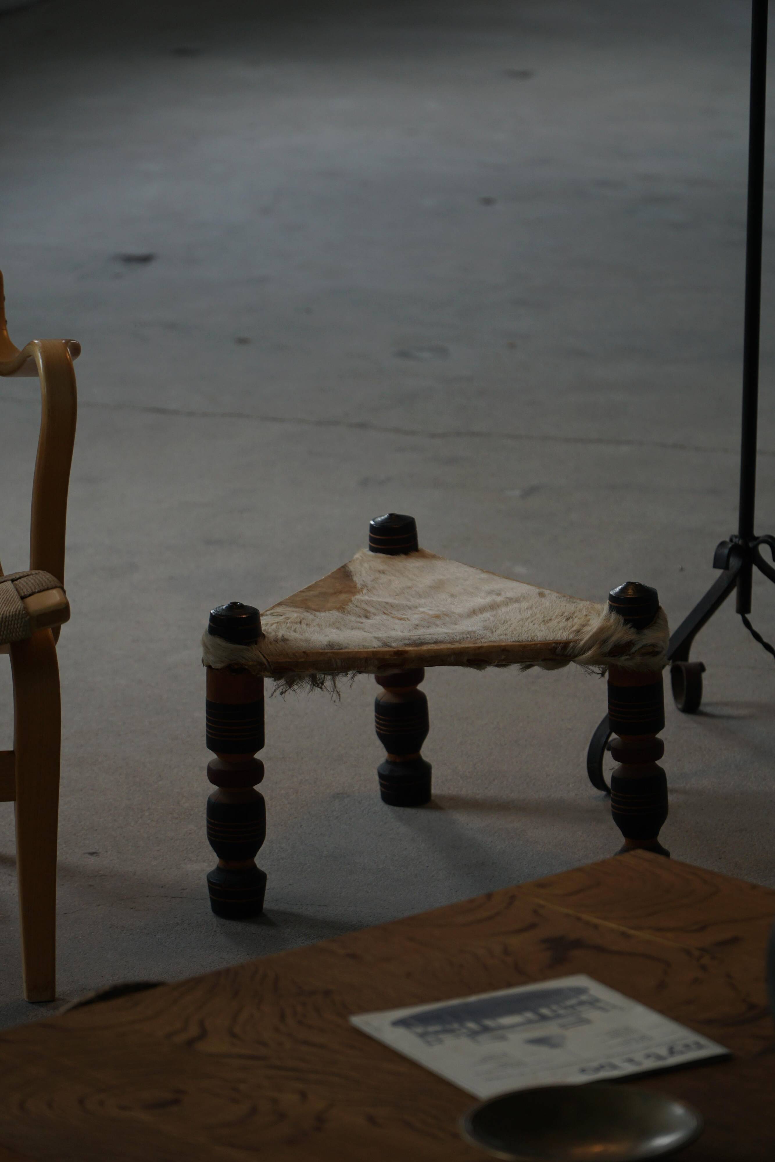 Vintage African artisanal stool, triangular shape with 3 legs, cowhide, 20th century.