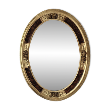 Antique medallion mirror with a gilded and relief-carved frame.