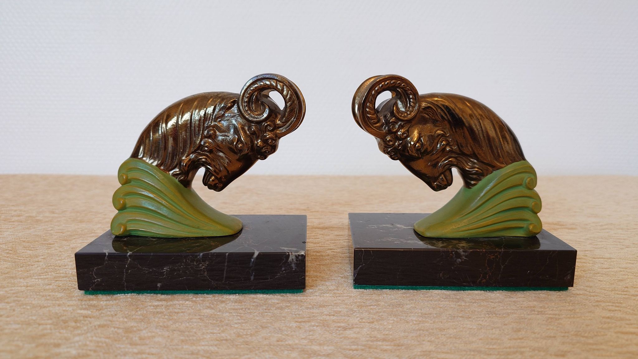 Art Deco pair of bookends with ram's heads, patinated metal and black marble.