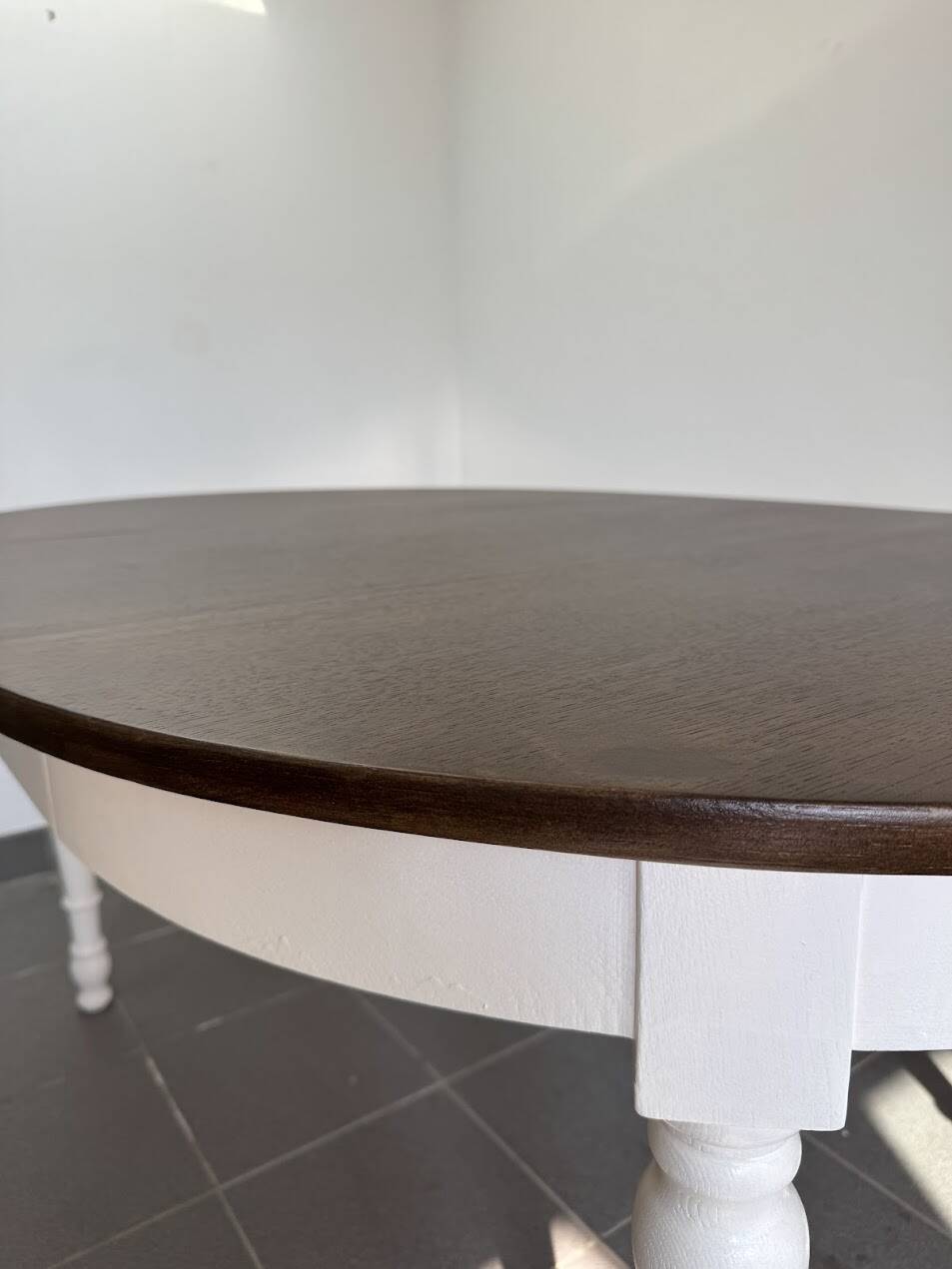 Restored solid wood round table with integrated extensions.