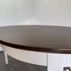 Restored solid wood round table with integrated extensions.