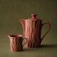 Vintage tea or coffee service in 1970s ceramic, teapot with lid and milk jug, rust orange with retro striped pattern, mid-century decoration, gift idea.