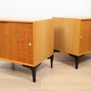 A pair of vintage mid-century bedside tables with oak sliding doors
