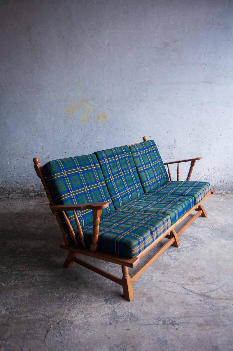 Canapé 3 places en chêne style années 50, avec tissu à carreaux vert-bleu et accoudoirs à fuseaux tournés.