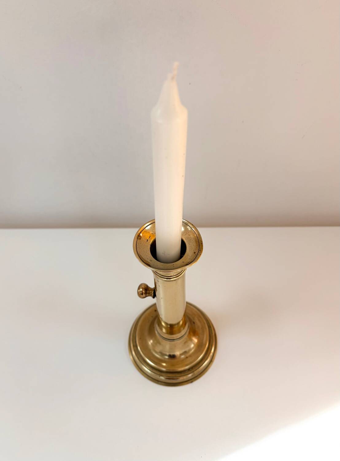 Old brass candlestick with push button.