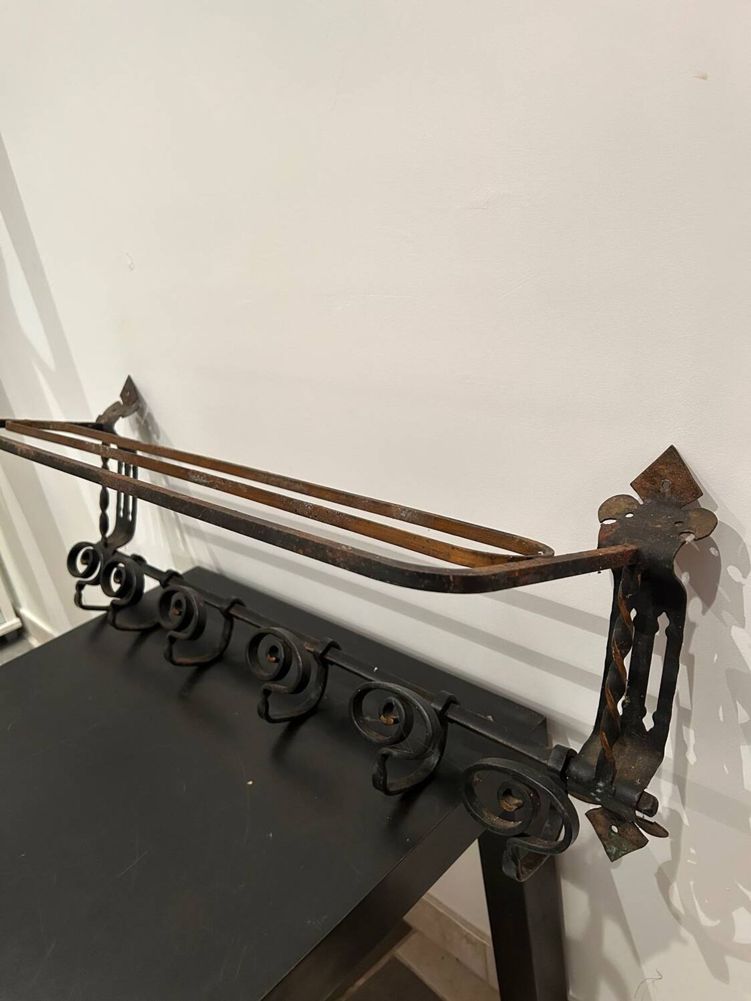 Large antique wall-mounted coat rack in wrought iron.