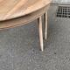 Round extendable dining table stripped in solid raw walnut with a central leg.