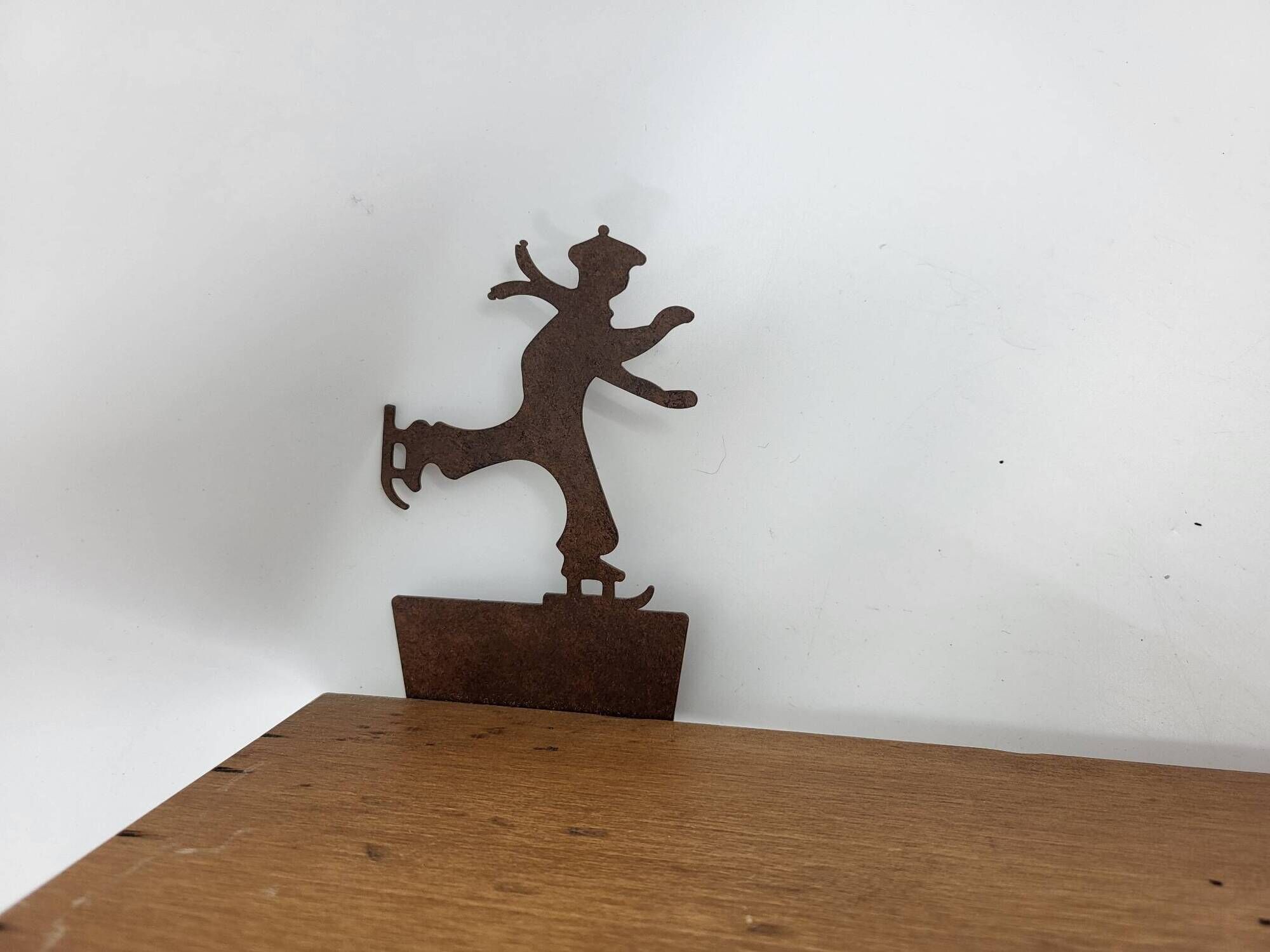 Wall shelf in wood and metal with a decoration of ice skaters.