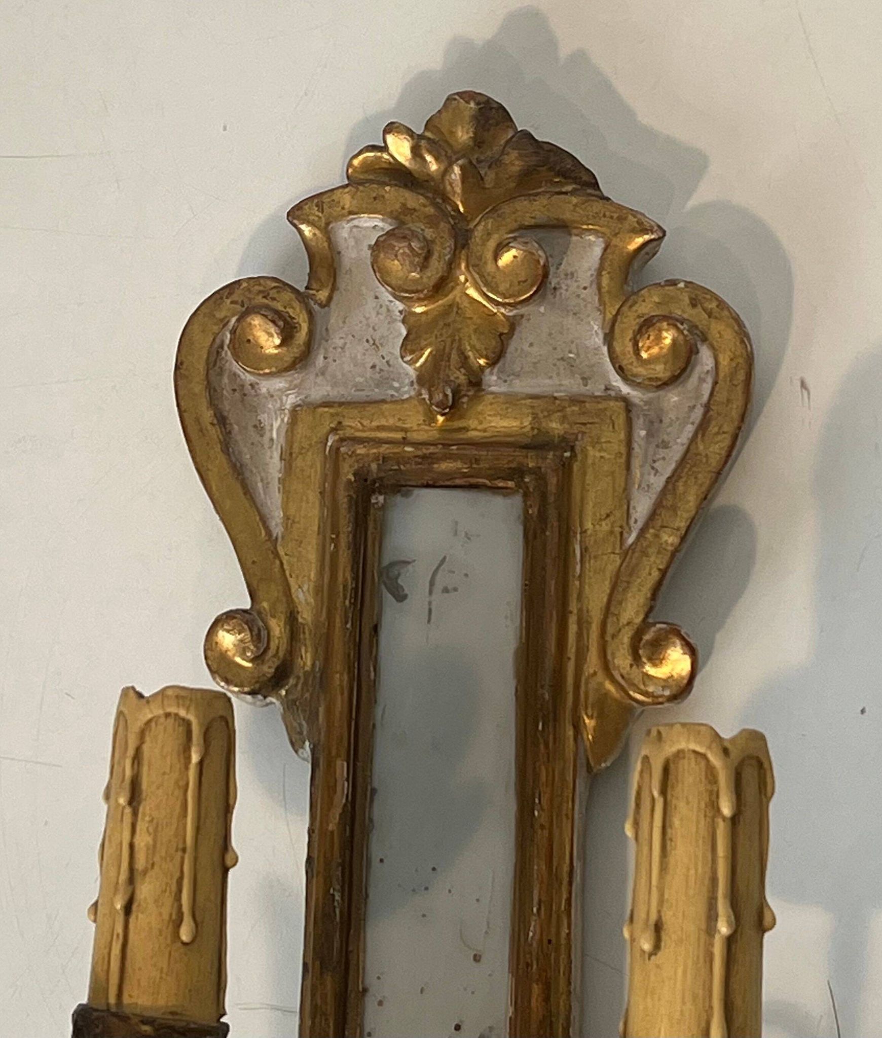 Pair of wall sconces in carved wood and silvered and gilded patinated metal with a central mirror.