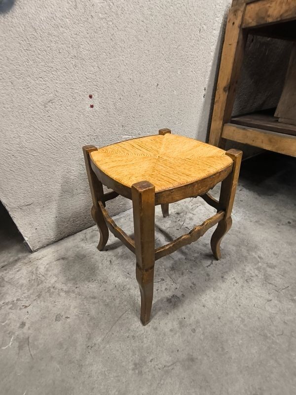 Rustic wooden stool with a straw seat.