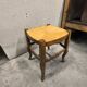 Rustic wooden stool with a straw seat.