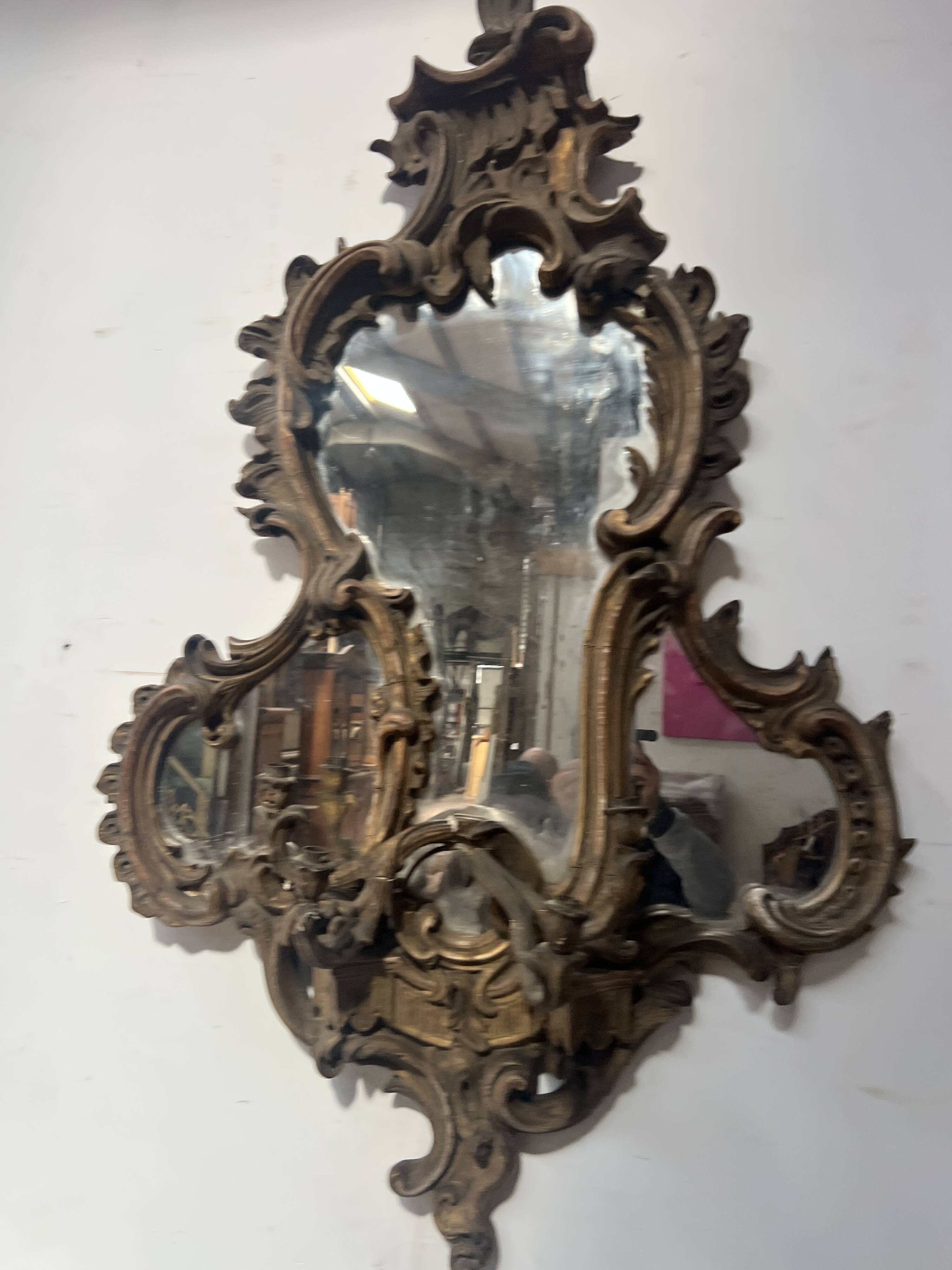 Mirror with a decorative frame featuring a four-light wall sconce, 19th century.