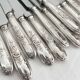 12 antique silver-plated knives with acanthus shell decoration and stainless steel blades.