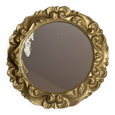 Round wooden mirror in golden colour.