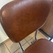 Two brown faux leather chairs.