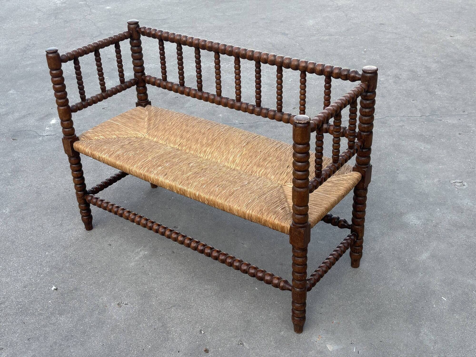 Vintage 'bobbin' bench with a rush seat, 1920s design with armrests.