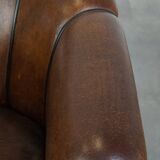 Fauteuil club en cuir de mouton foncé avec passepoil noir