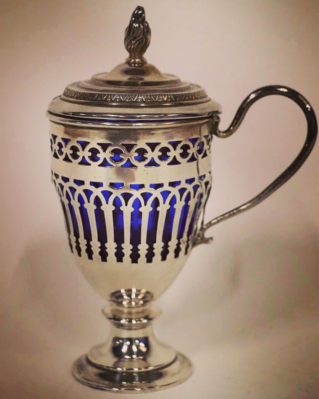 Solid silver mustard tree whose open body rests on a round pedestal.