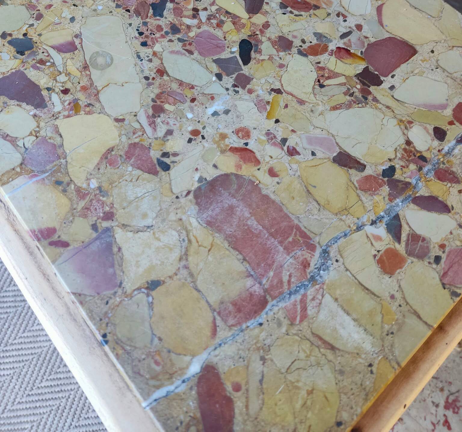Small Art Deco bedside table in light wood with a terrazzo effect top.